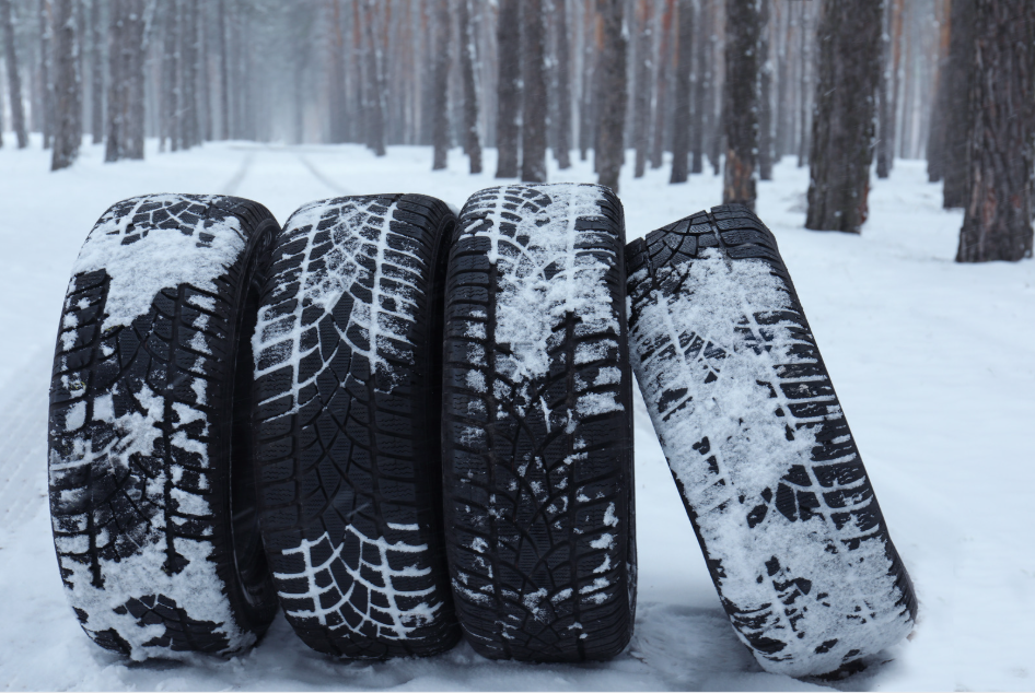 Four winter tyres covered in snow, standing on a forest road